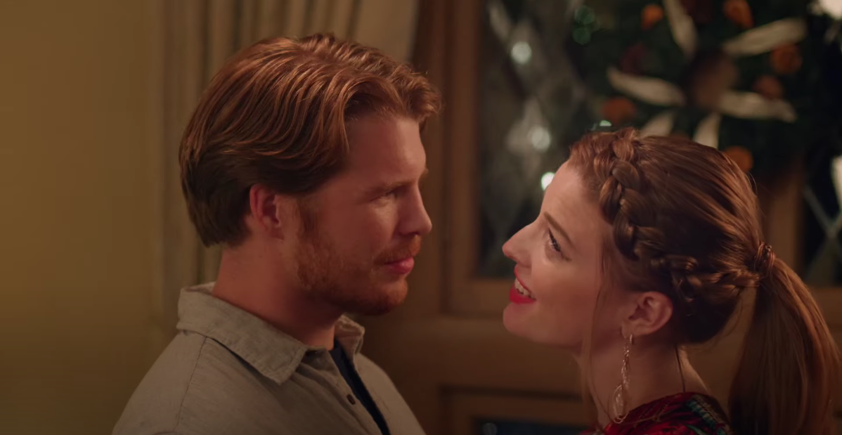 Felicity and her love interest are standing in front of each other. She is the object of his attention while her gaze appears distracted as if she's looking up and past him.